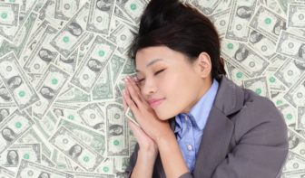 Image of woman in a business suit sleeping on a bed of money